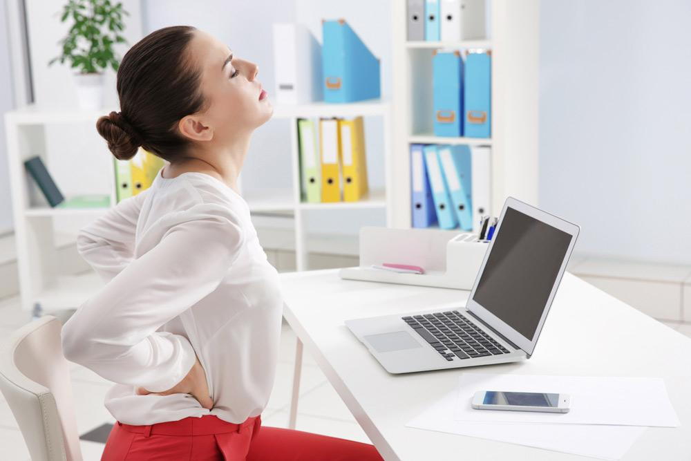 Woman with back pain from bad ergonomics.
